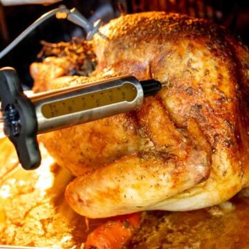 a beautiful golden brown turkey being injected with a flavorful butter mixture.