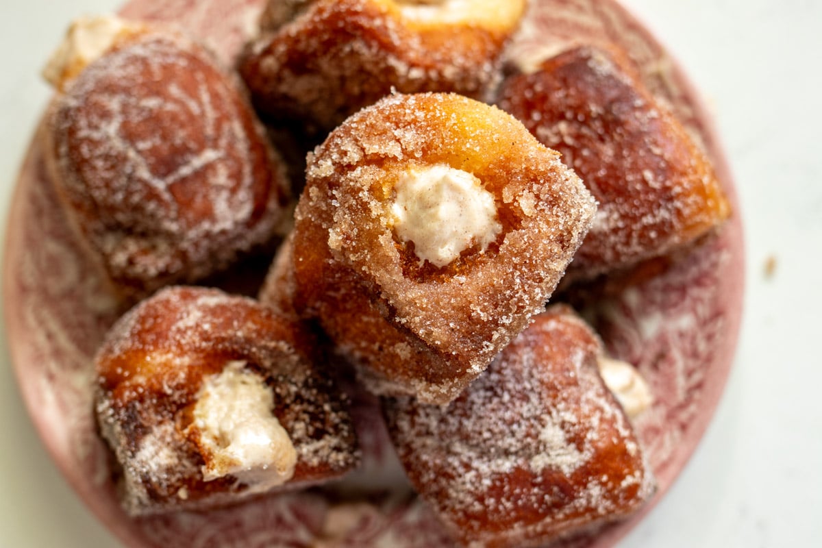 an overhead view of a plate of pumpkin spice donuts that are bursting with pumpkin spice cream cheese.