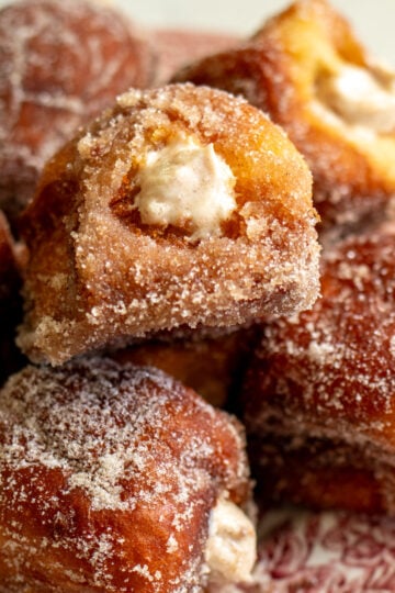 an overhead view of a plate of pumpkin spice donuts that are bursting with pumpkin spice cream cheese.