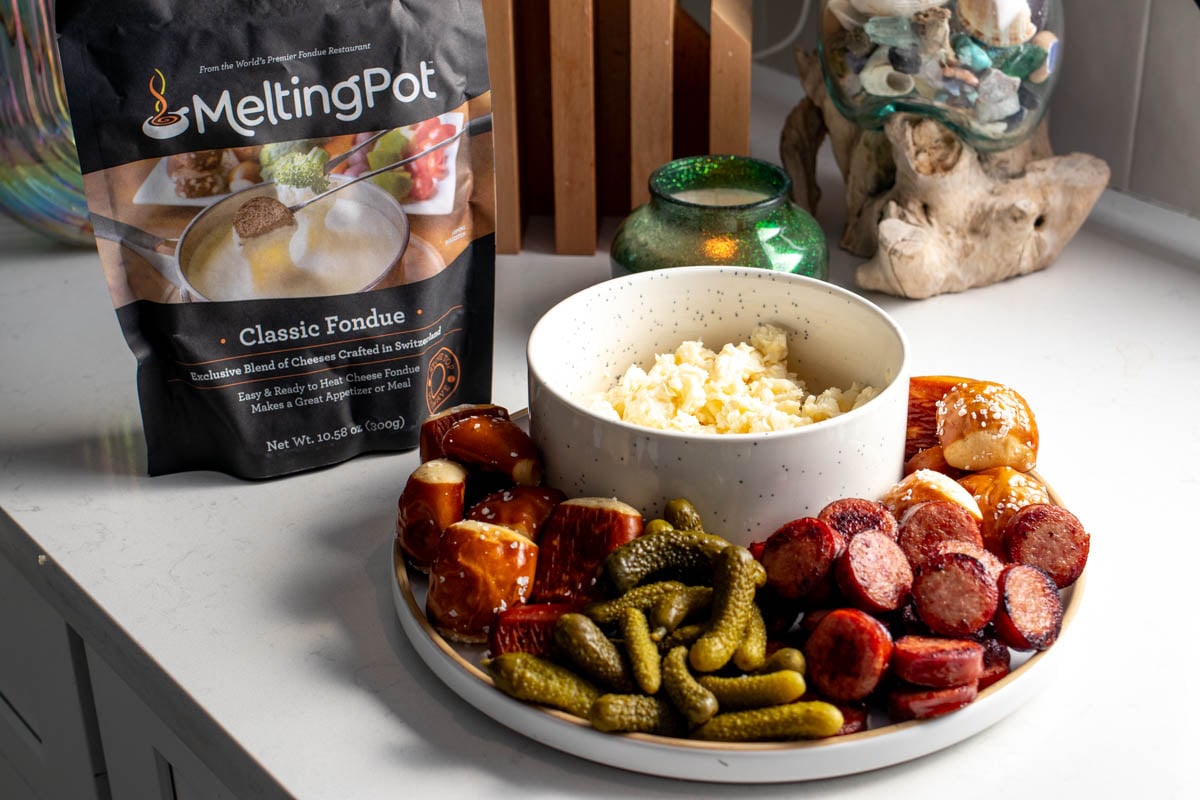 a bag of melting pot cheese fondue on a countertop with colorful fondue dippers. 