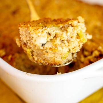 a scoop of oyster dressing in a gold spoon over the top of the baking dish.