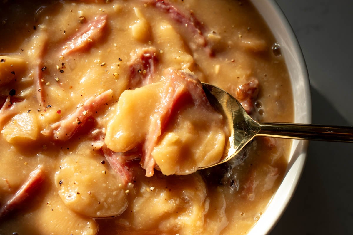 a golden spoon holding a scoop of crockpot soup beans.