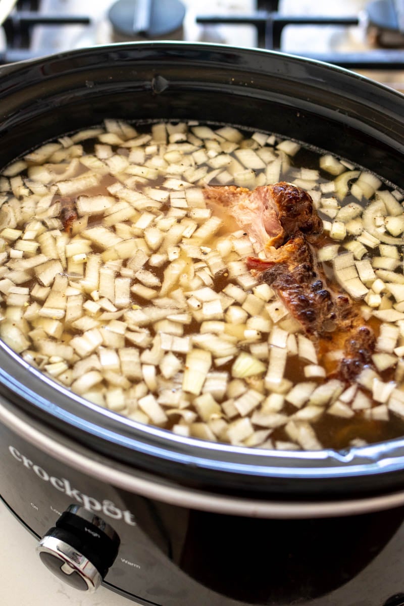 all of the ingredients needed to make crockpot soup beans in a black crockpot.