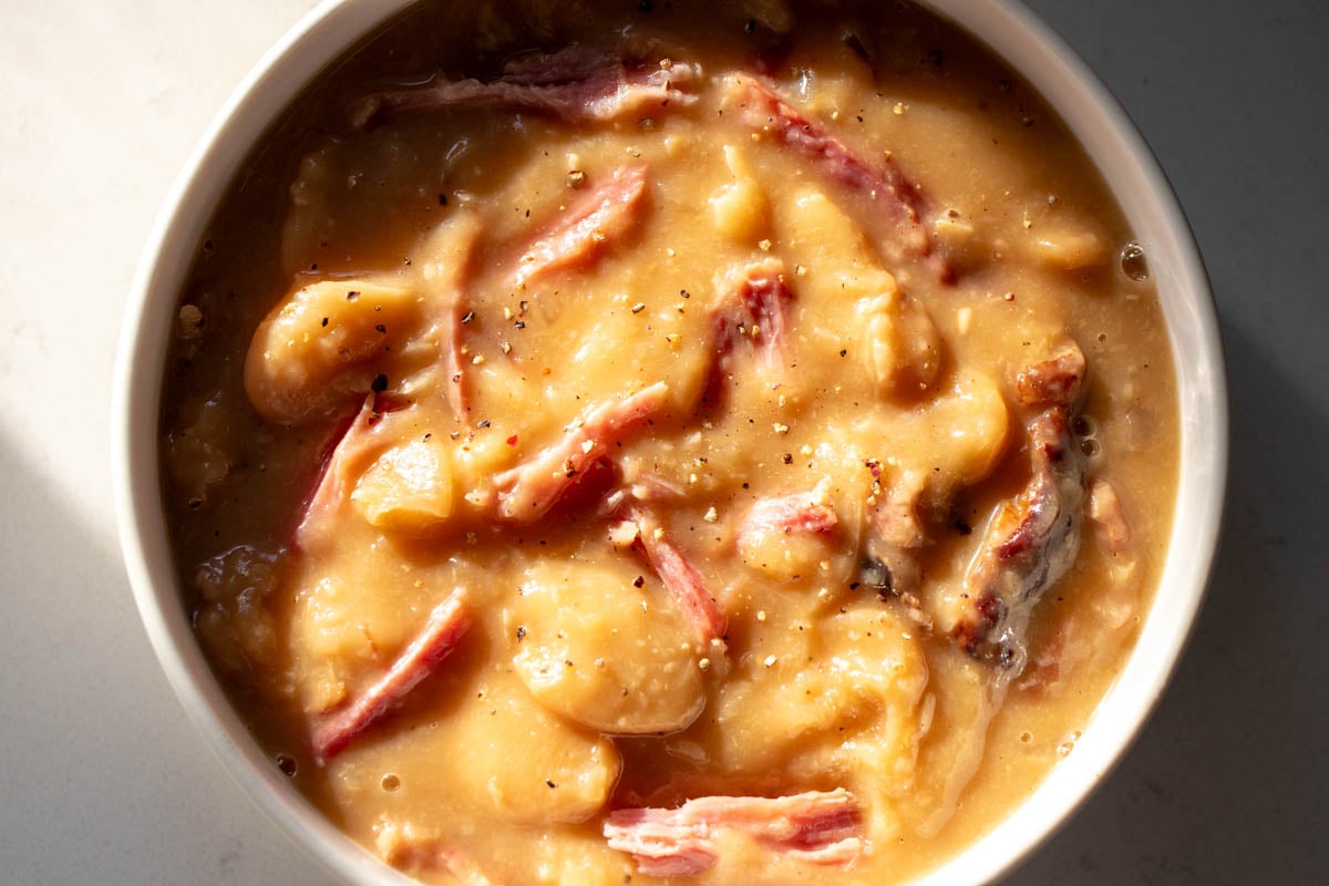 a small white bowl full of delicious southern crockpot soup beans with shreds of ham on top.