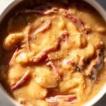a small white bowl full of delicious southern crockpot soup beans with shreds of ham on top.