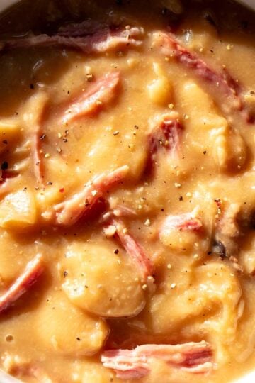 a small white bowl full of delicious southern crockpot soup beans with shreds of ham on top.