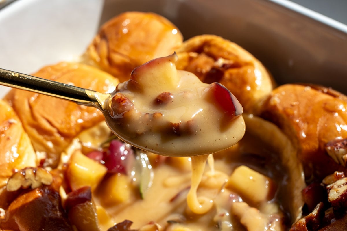 a spoon holding a scoop of melted brie and caramleized apples.