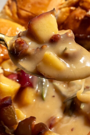 a spoon holding a scoop of melted brie and caramleized apples.