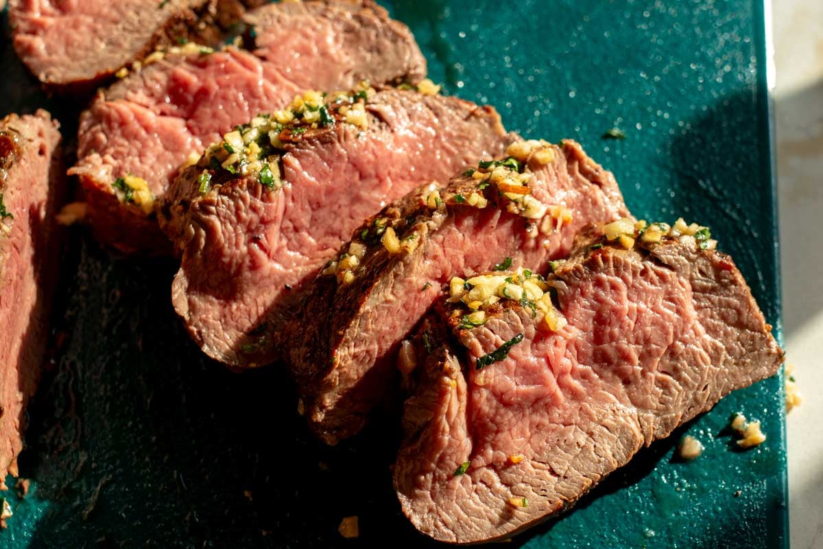 a cutting board full of a whole sliced beef tenderloin.
