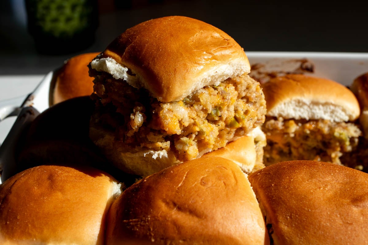 a baking dish full of jalapeno popper sausage sliders with one sitting on top.