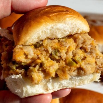 a hand holding a single jalapeno popper sausage slider.