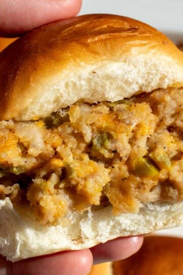 a hand holding a single jalapeno popper sausage slider.