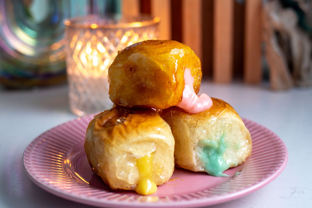 colorful icing oozing out of a tanghulu coated kings hawaiian sweet roll.