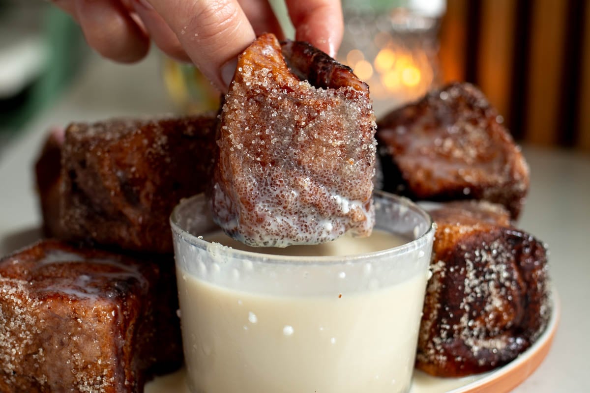 a coconut ube hawaiian roll french toast bite dipped in tres leches mixture.