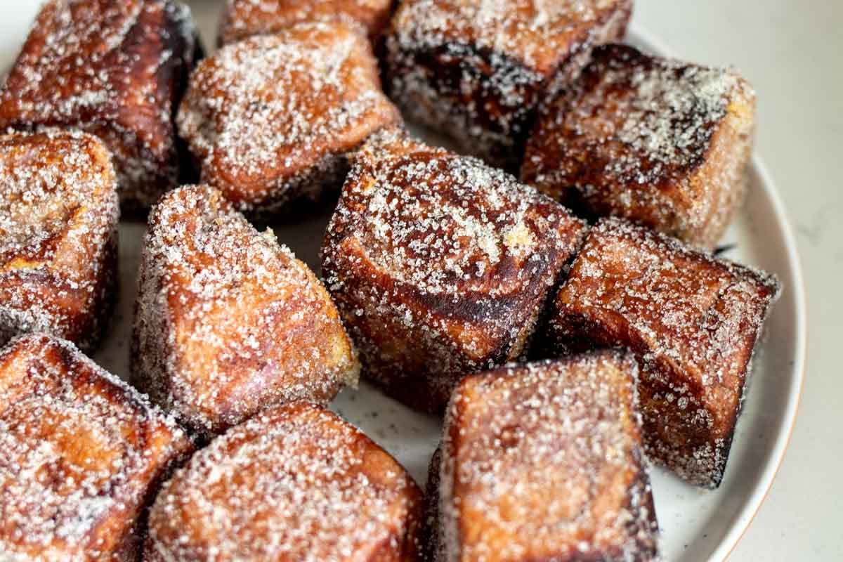 a large plate of sugar coated coconut ube hawaiian roll french toast.