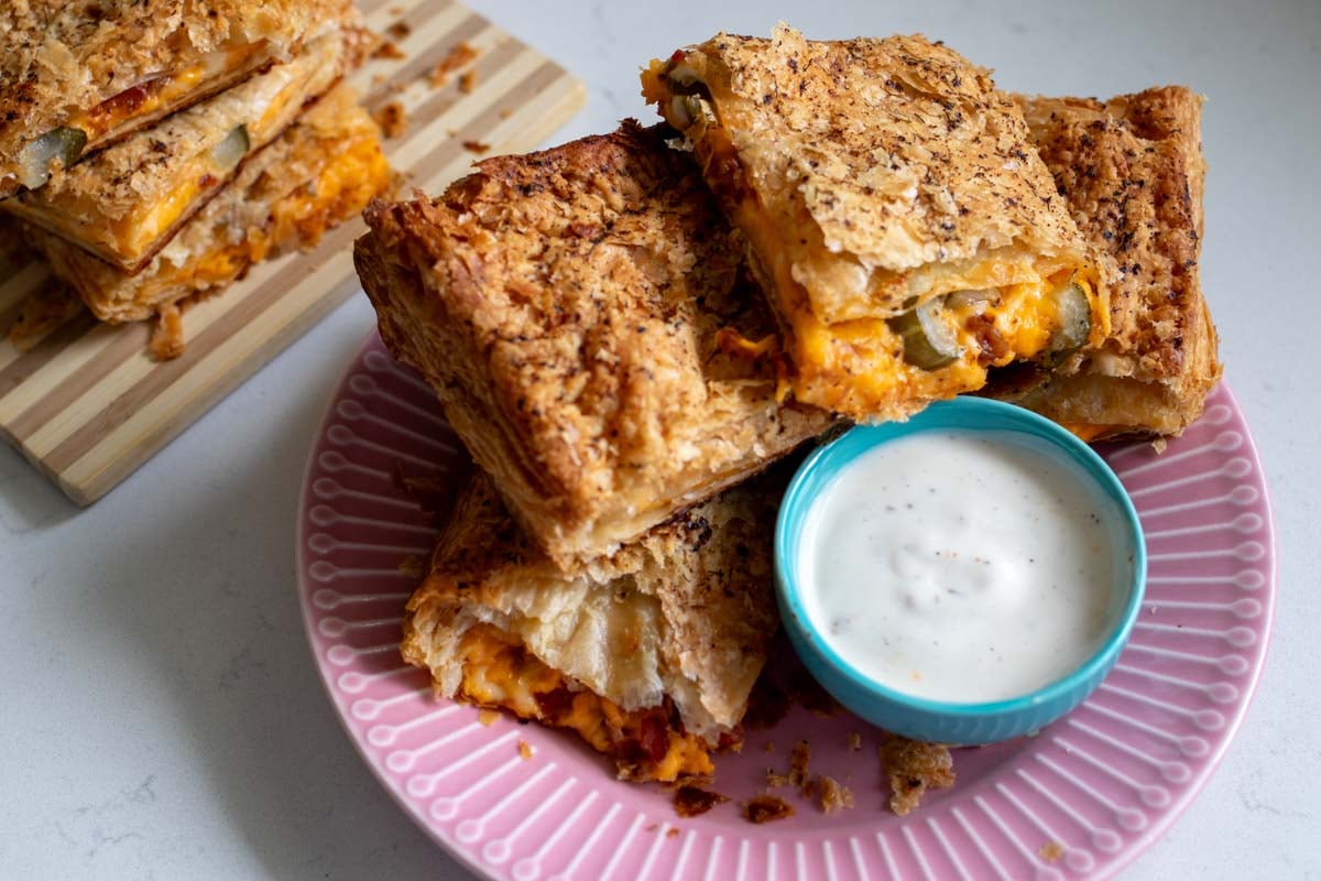 a pink plate full of grilled cheese pillows with a side of ranch to dip it in.