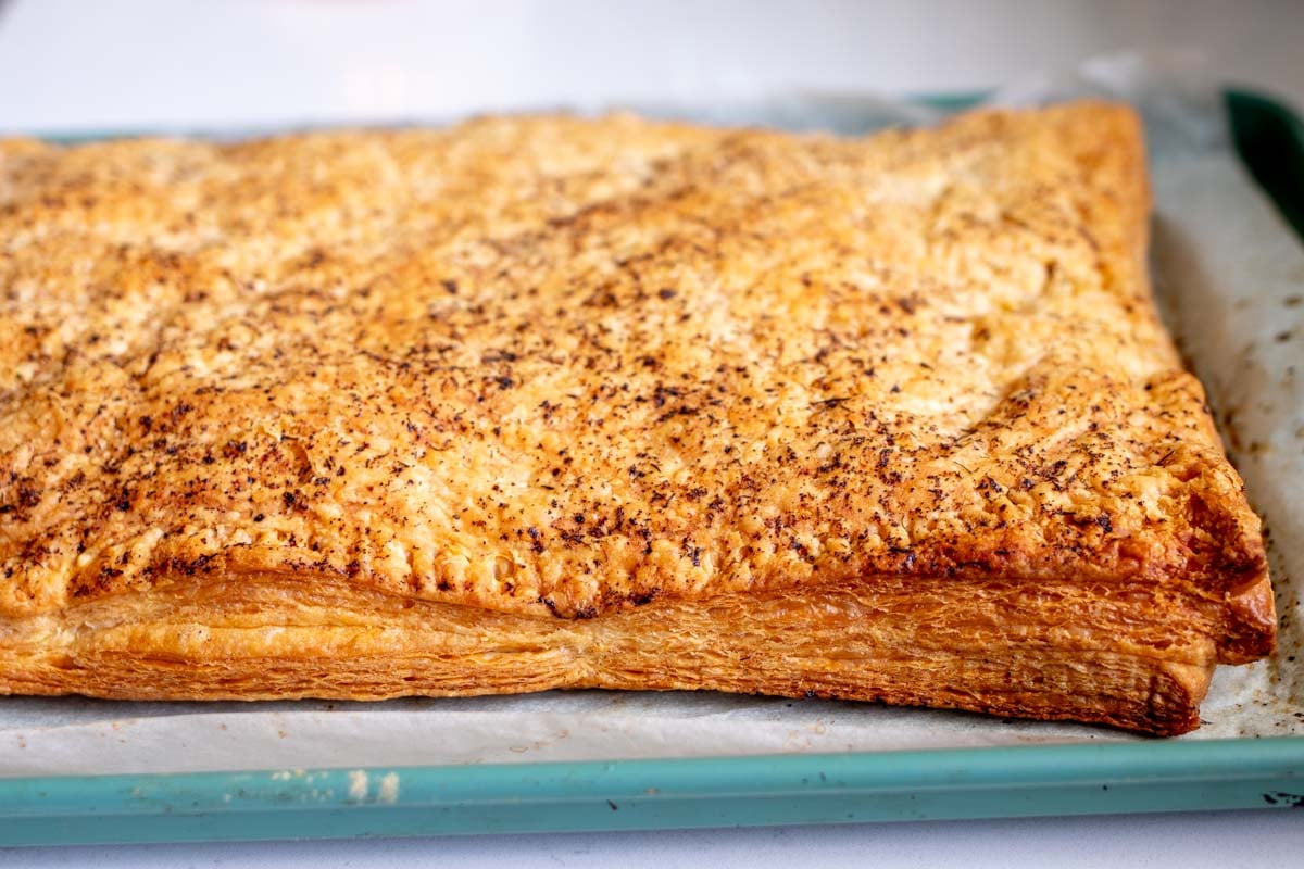 cooked puff pastry showing all the buttery layers on a baking sheet.