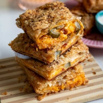 a stack of grilled cheese pillow pockets with bacon and pickles oozing out.