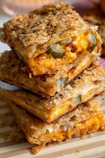 a stack of grilled cheese pillow pockets with bacon and pickles oozing out.