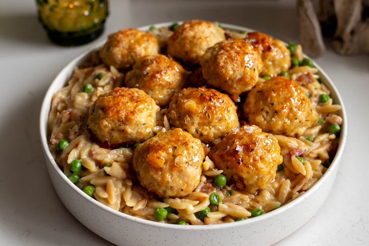 a big white bowl full of ground chicken meatballs over creamy orzo.