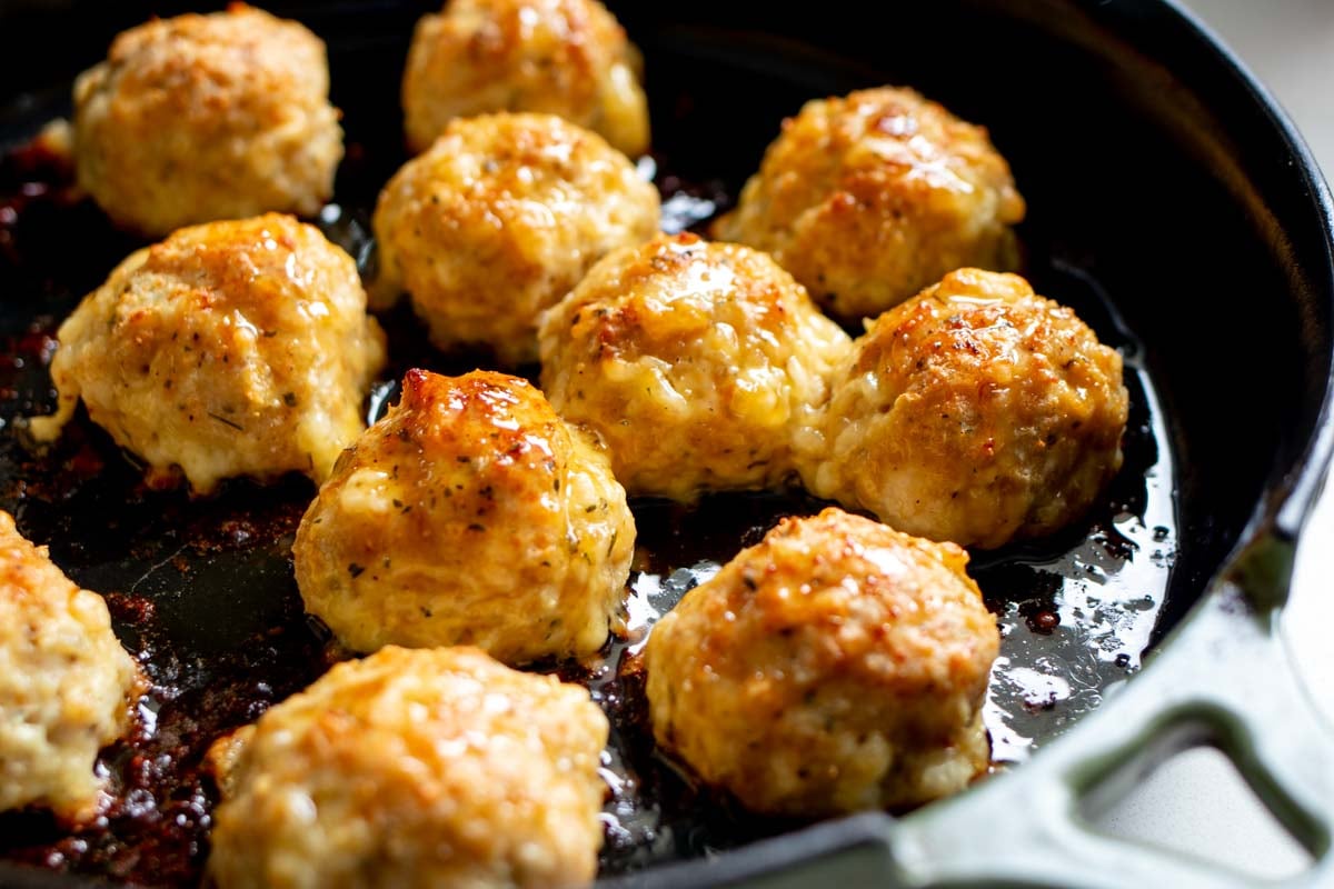 sticky chicken meatballs in a cast iron skillet after baking.