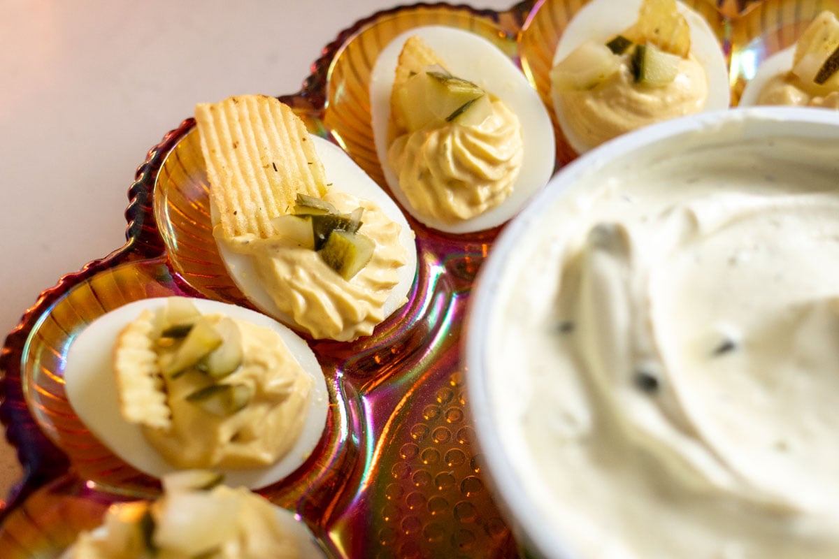 an old fashioned deviled egg plate topped with dill pickle deviled eggs and a creamy dill pickle dip.