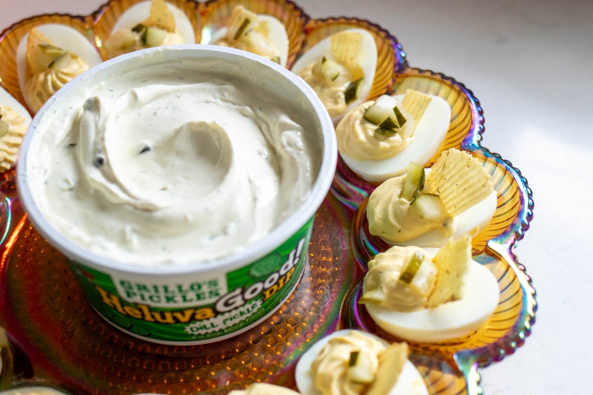 a bowl of dill pickle dip with deviled eggs around it.
