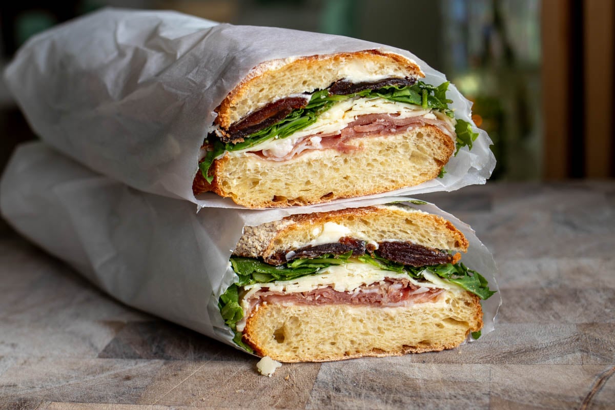 the cross section view of two halves of a sub sandwich sitting on a cutting board.