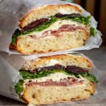 two halves of a prosciutto butter sandwich stacked on top of each other.