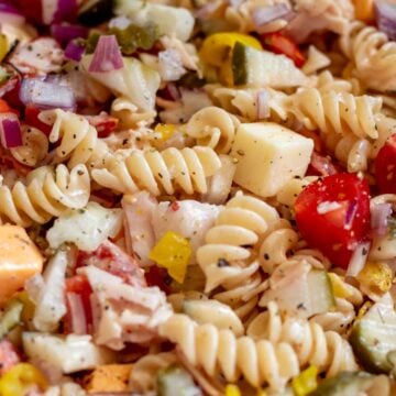 a close up view of a sub in a tub pasta salad with a focus on the colorful ingredients.