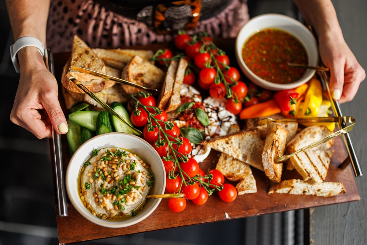 a beautiful platter of tomatoes, veggies, hummus and more. 