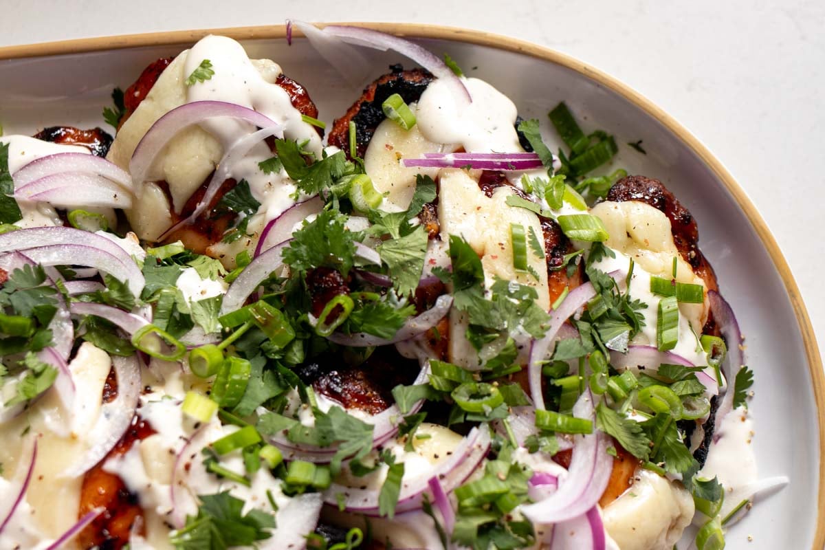 a white dinner platter full of bbq grilled chicken with colorful toppings.