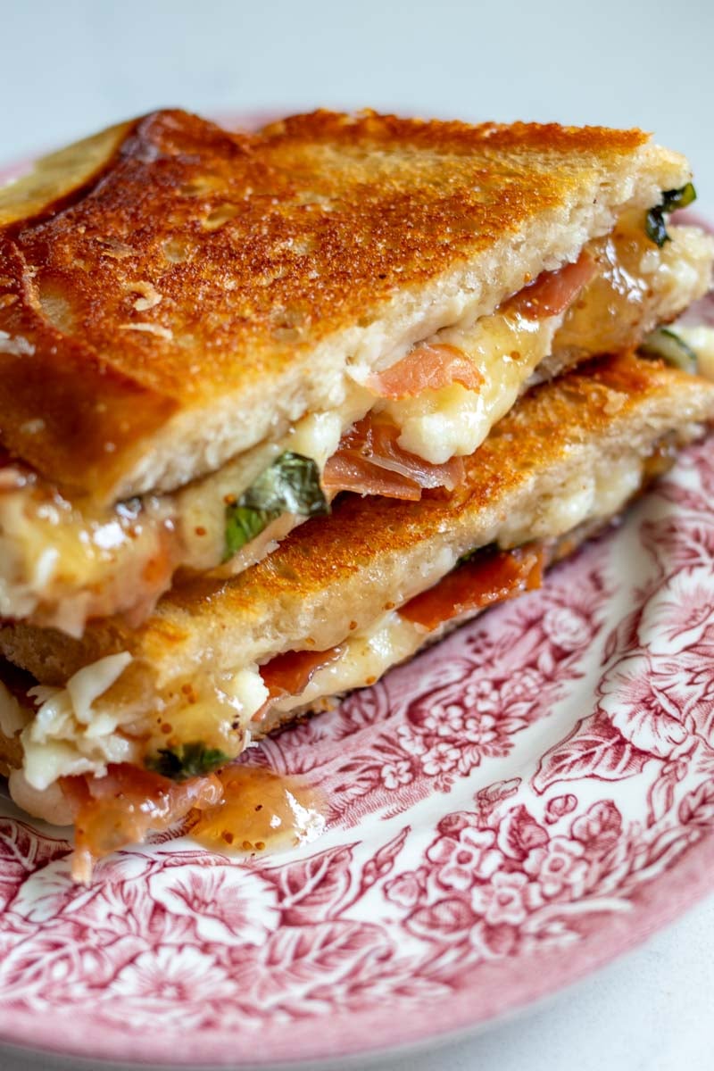 a birds eye view of a gourmet grilled cheese sandwich with fig jam, prosciutto, basil and white cheddar.