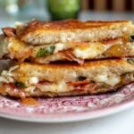 a gourmet grilled cheese on a antique plate on a white table top.