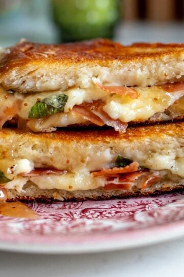 a gourmet grilled cheese on a antique plate on a white table top.