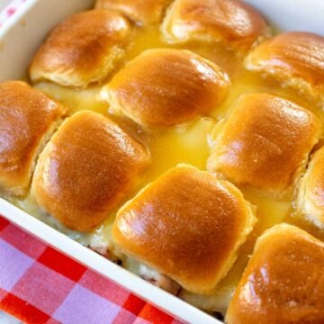 a baking dish filled with golden glazed ham and cheese sliders.