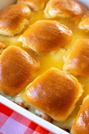 a baking dish filled with golden glazed ham and cheese sliders.