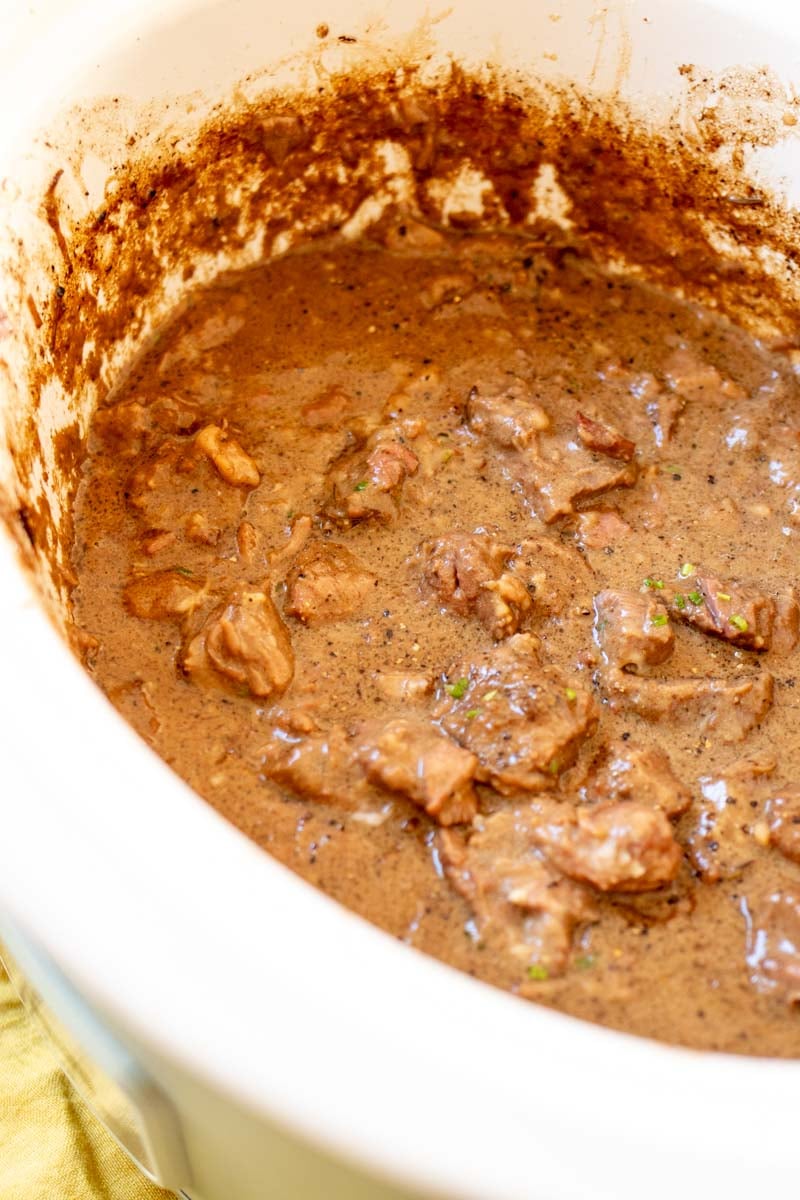 a crockpot filled with steak bites and a creamy au poivre sauce.