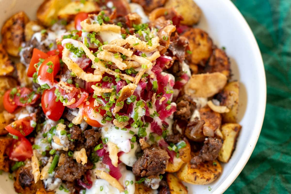 a close up of the texture of the burger bowl with colorful toppings and white sauce.