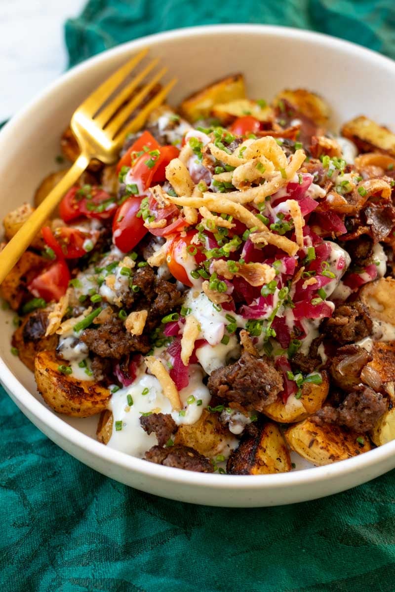 a ground beef and potato bowl on a table with a green napkin.