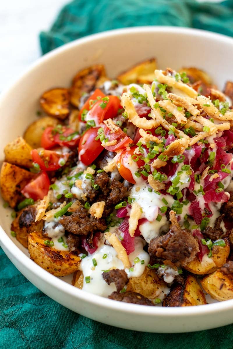an overhead view of a burger bowl with colorful toppings and dripping sauce.