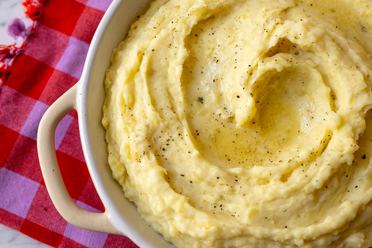 an overhead view of a white serving bowl filled with boursin mashed potatoes.