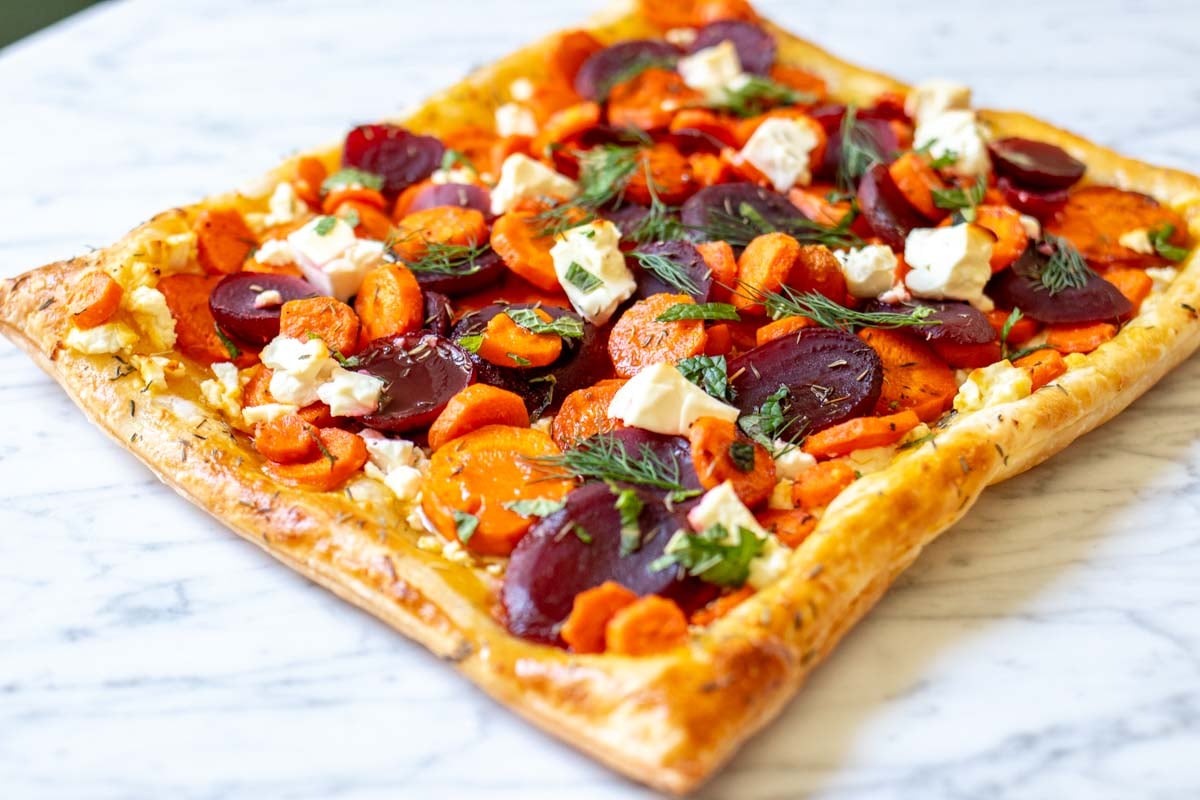 a bright and colorful carrot and feta tart with pickled beets and fresh herbs.