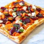 a bright and colorful carrot and feta tart with pickled beets and fresh herbs.