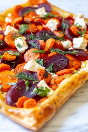 a bright and colorful carrot and feta tart with pickled beets and fresh herbs.