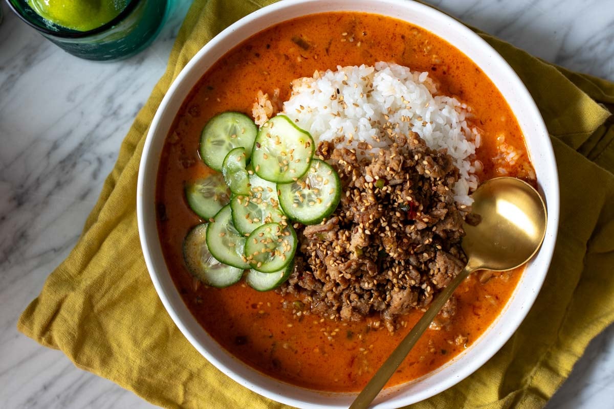 an overhead view of the viral broth bowl with bright red curry broth, ground turkey, rice and cucumbers.