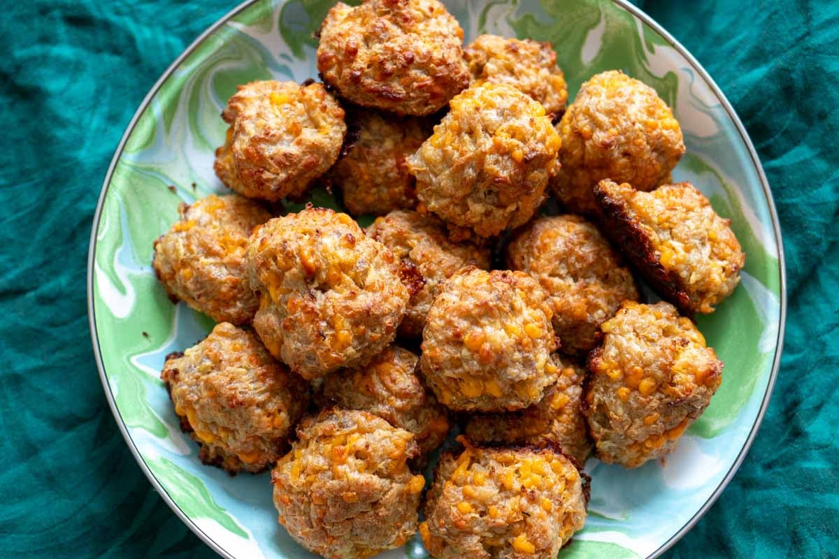 a plate full of cheddar apple sausage balls on a blue plate with a green napkin in the background.