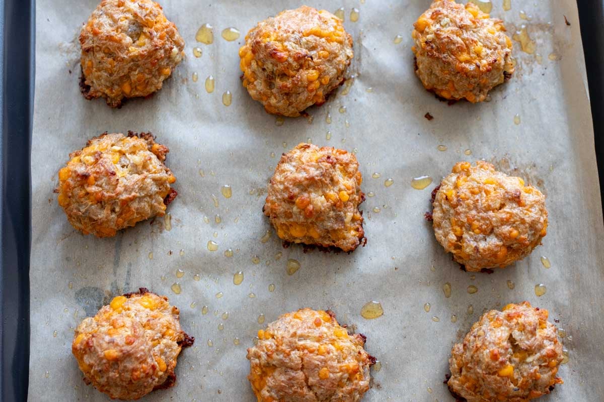 an overhead view of a baking dish full of freshly baked sausage balls with cheddar and apple.