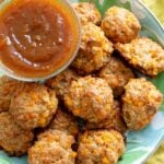 cheddar apple sausage balls on a plate with apple butter dipping sauce on a yellow napkin.