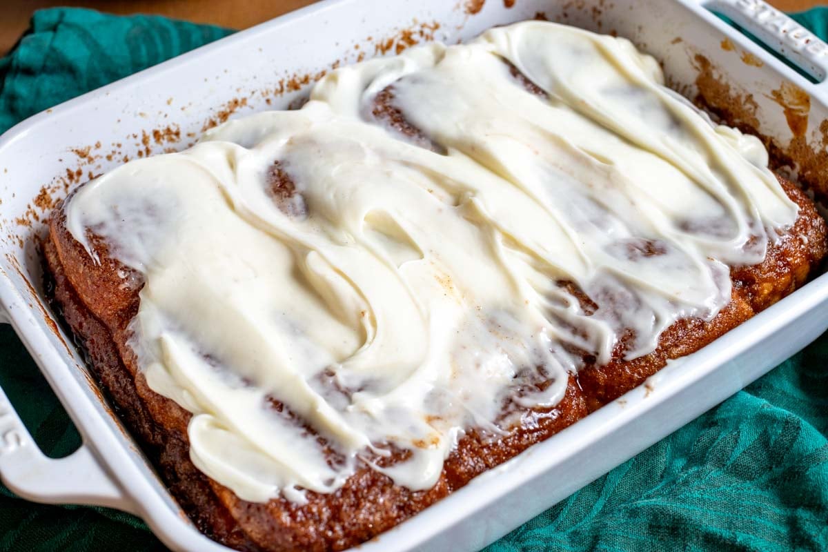a baking dish full of hawaiian roll cinnamon rolls with cream cheese icing.